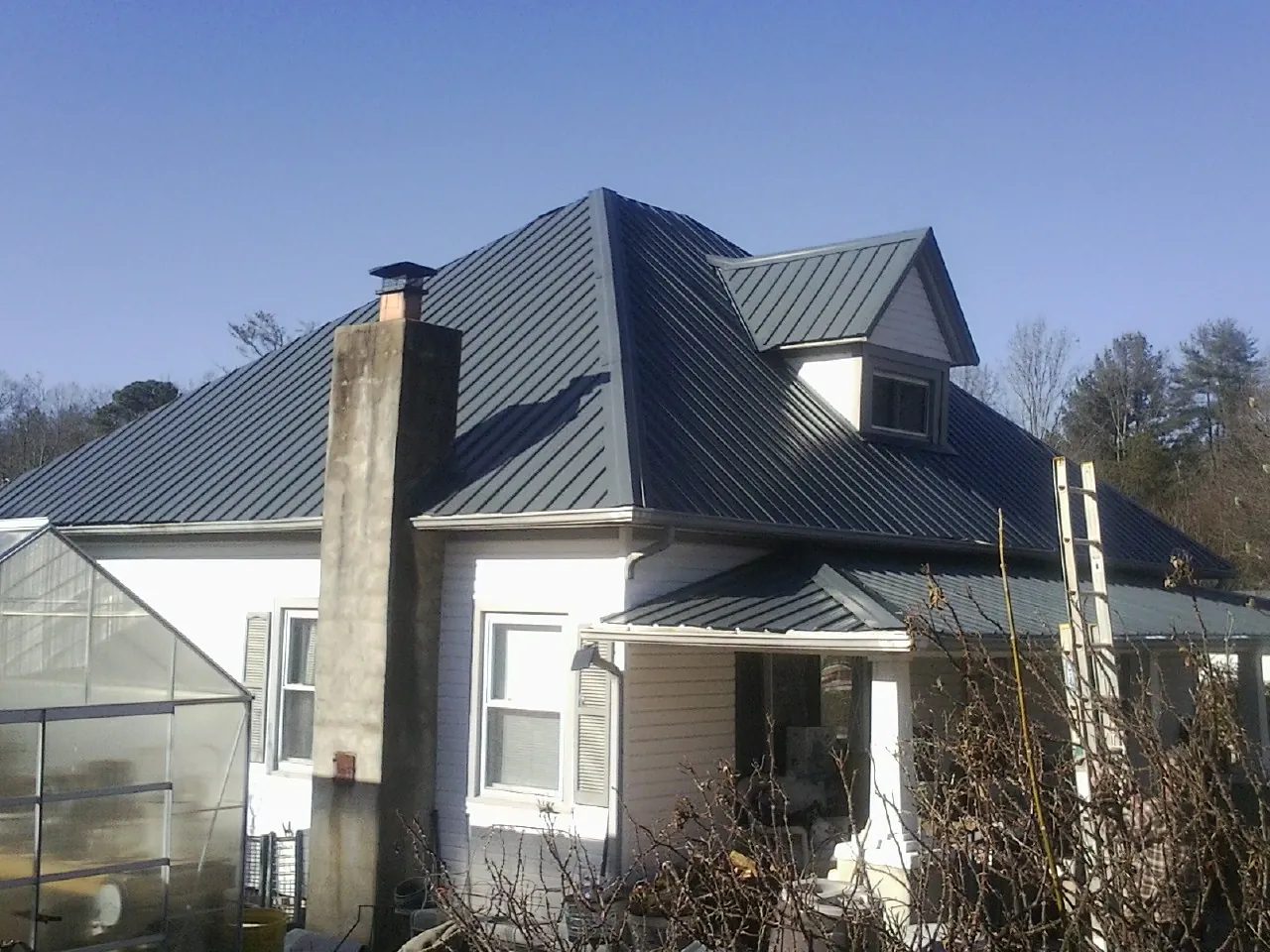 Dark blue standing seam metal roof on a white farmhouse with dormer — Slate & Tile Roof Repair by Roofing Brothers in Lake Havasu City