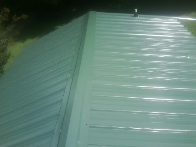 New green metal panels meeting at the ridge of a roof — Flat Roof Repair work by our crew in Lake Havasu City