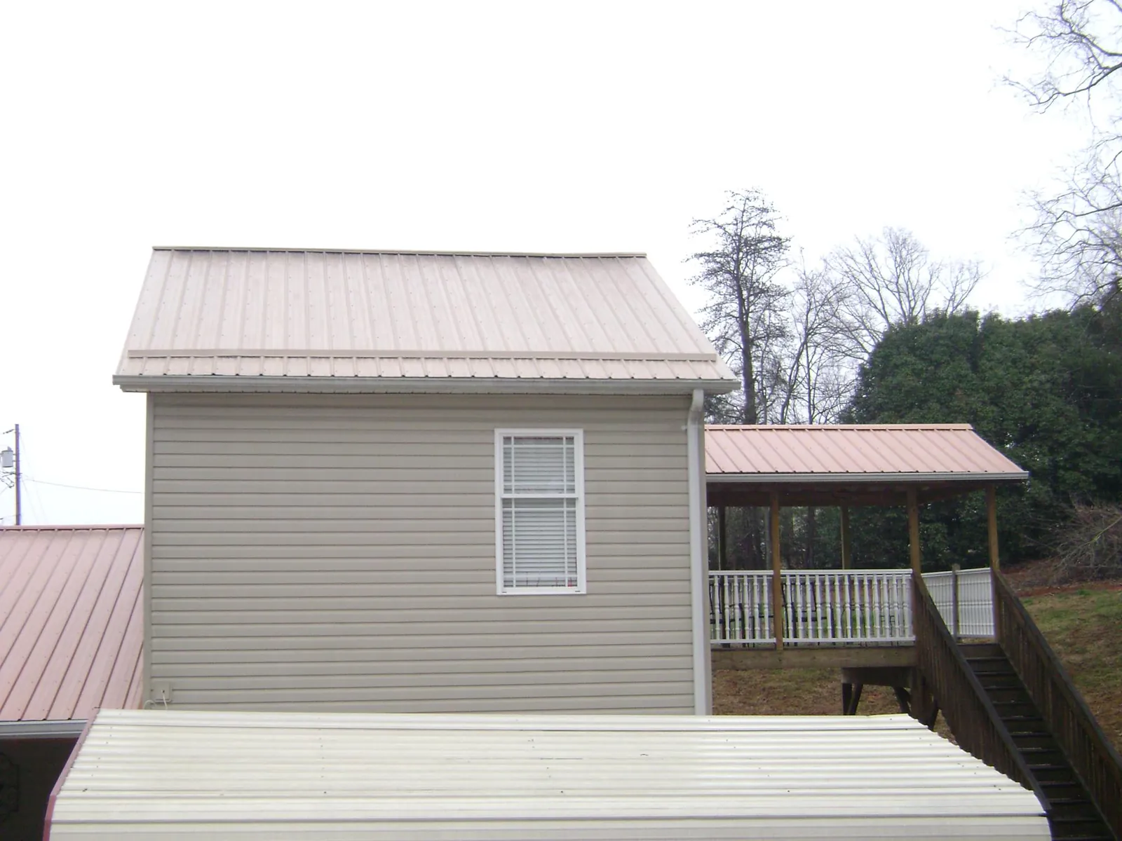 Tan metal roofs on a two story addition and attached porch, from a Roof Replacement job in Lake Havasu City
