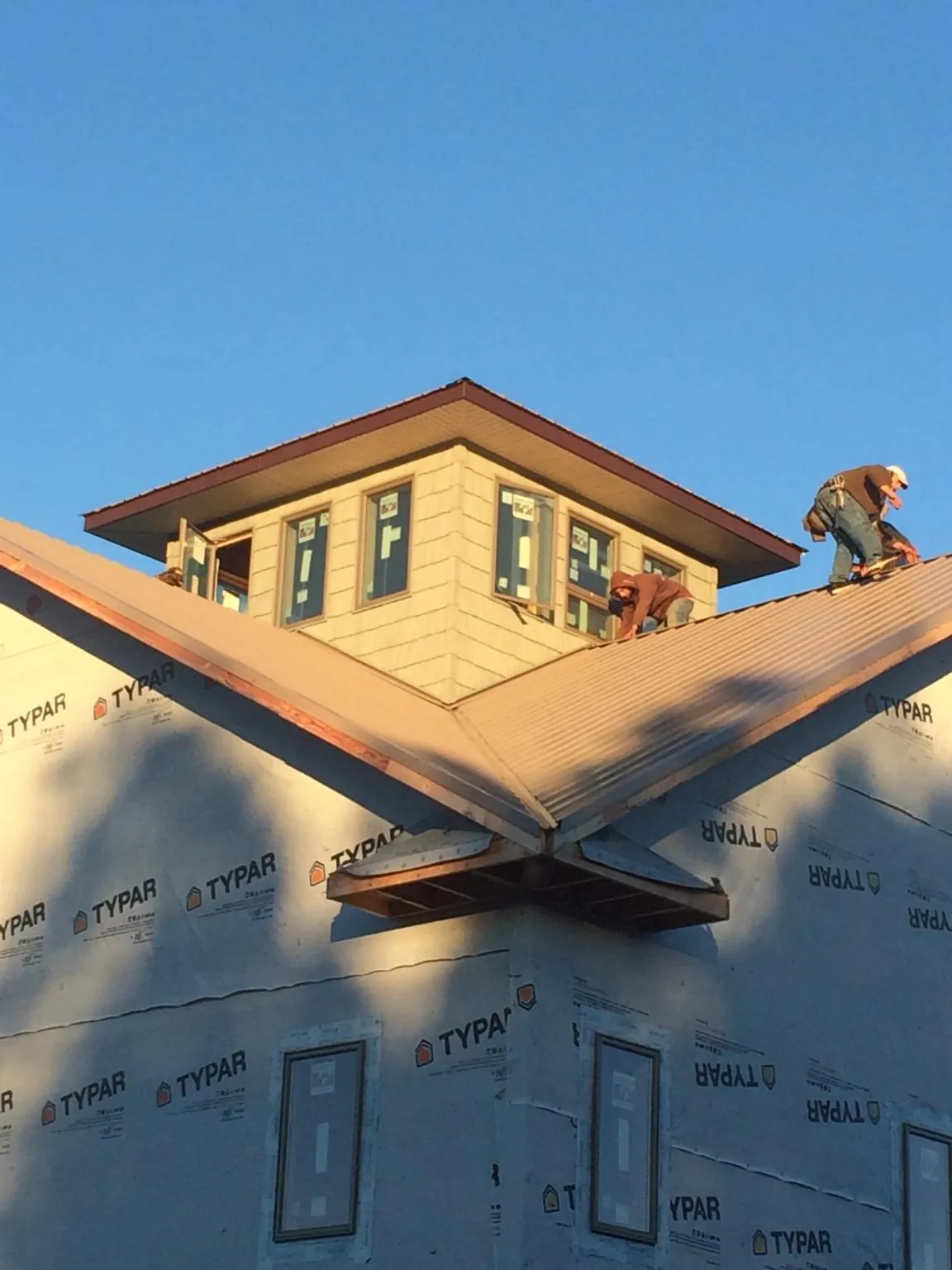 Roofers working around a rooftop cupola on a new metal roof at sunset — Roof Waterproofing in Lake Havasu City by Roofing Brothers
